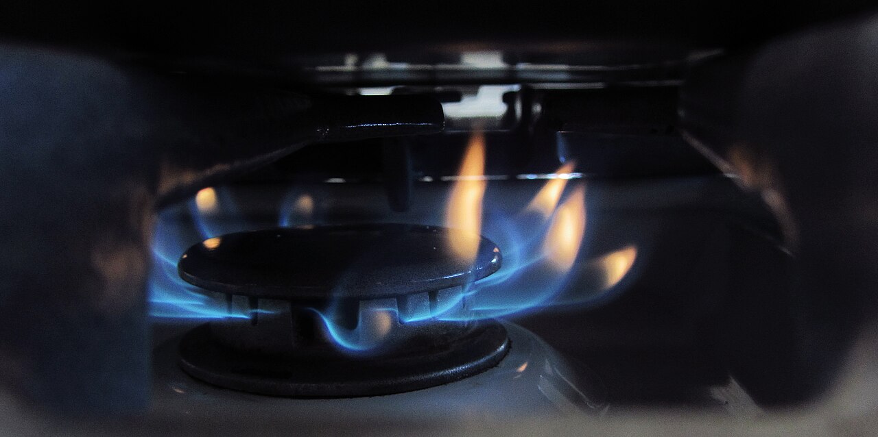 Close-up of a gas stove burner with blue flame